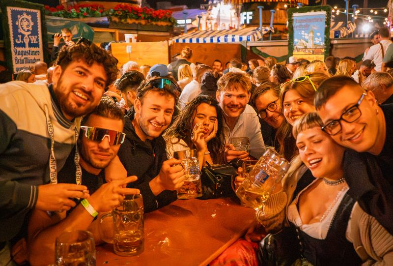 Freundesrunde mit Maßkrügen am Tisch im Festzelt