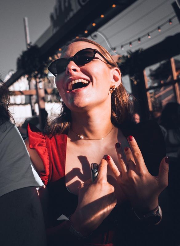 Lachende Frau mit Sonnenbrille im Biergarten